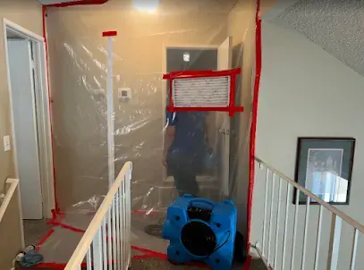 Plastic containment and an air mover set up at a stairway during a Highland dry-out