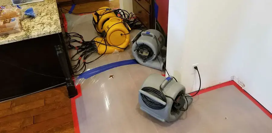 Air movers drying the floor beside a kitchen counter after a leak