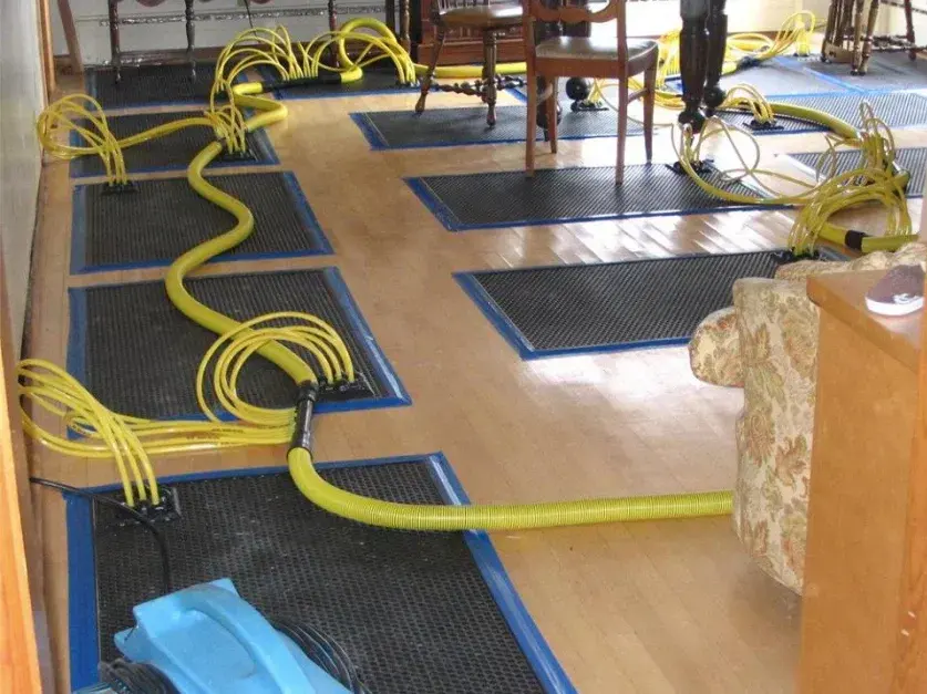 Floor drying mats, hoses and air movers drying a hardwood dining room in a Highland home