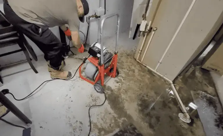 Drain machine clearing a backed-up floor drain during a Highland sewage cleanup