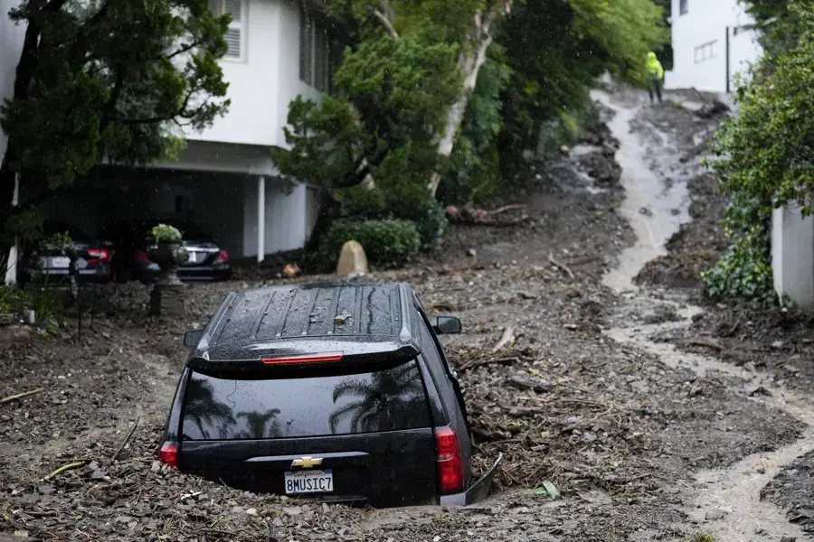 Mud and storm runoff around a car on a foothill street after a flash flood, storm flood cleanup for Highland